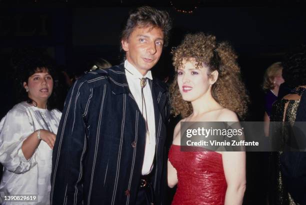 American singer Barry Manilow, wearing a blue jacket with white vertical stripes, a white shirt and a bolo tie, and American actress and singer...