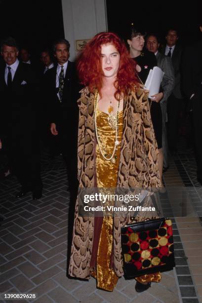 American actress Olivia Barash, wearing a long snakeskin-effect coat over an orange velvet evening gown, attends a party hosted by Entertainment...