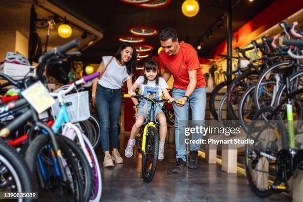 parents buying a bicycle for their daughter in a bike store - buying a bike bildbanksfoton och bilder