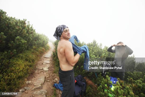 two men changing clothes after rain on mountain trail - wandern regen stock-fotos und bilder