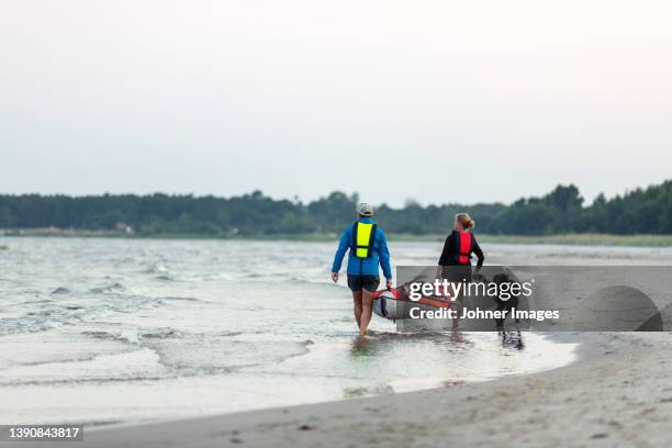 couple carrying kayak at sea - carrying kayak stock pictures, royalty-free photos & images