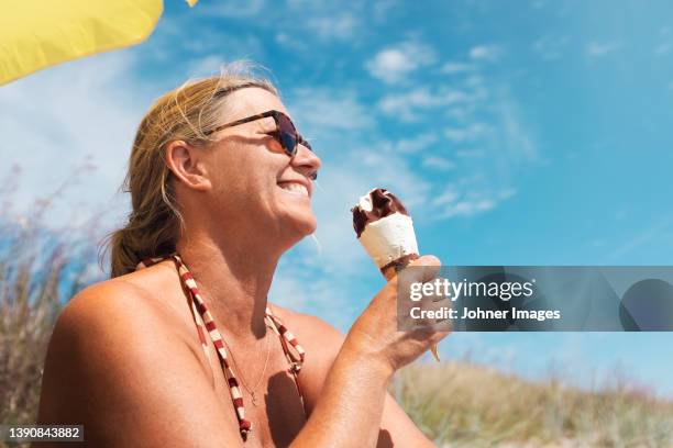 smiling woman having ice-cream - woman ice cream stock pictures, royalty-free photos & images