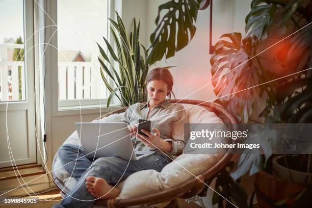 woman using smart phone and laptop at home - facial recognition technology stock-fotos und bilder