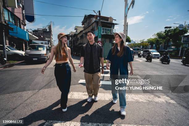 young people in asia and taiwan are talking and laughing while crossing the road. - street fashion asian stock pictures, royalty-free photos & images