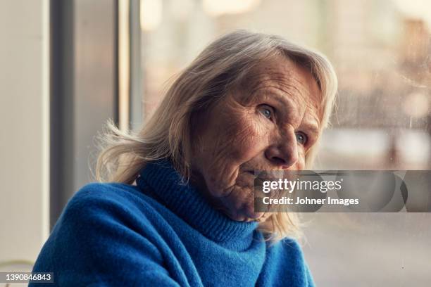 senior woman looking through window - elderly women bildbanksfoton och bilder