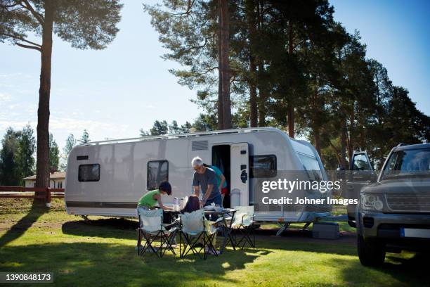 family having meal in front of camper trailer - caravan stockfoto's en -beelden