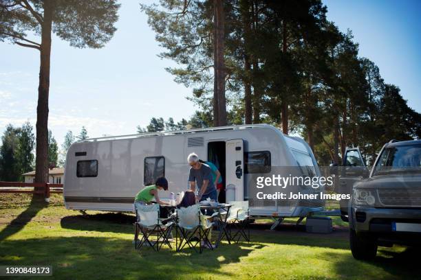 family having meal in front of camper trailer - camping trailer stock pictures, royalty-free photos & images