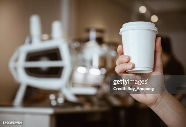 someone hand holding a paper cup of hot coffee in coffee shop. - takeaway coffee stockfoto's en -beelden