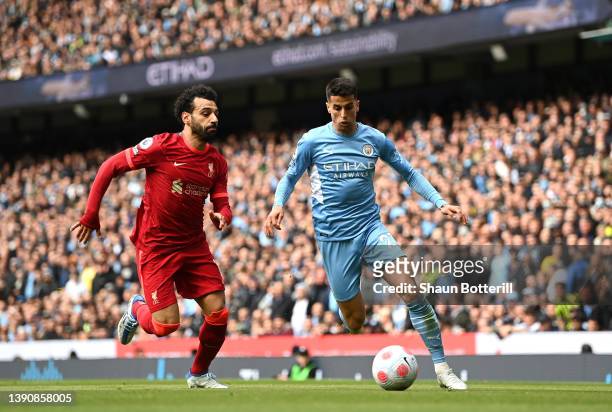 Joao Cancelo of Manchester City is challenged by Mohamed Salah of Liverpool during the Premier League match between Manchester City and Liverpool at...