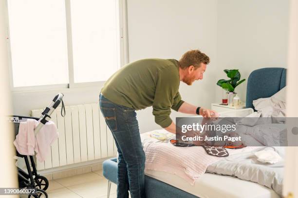 mature father changing his baby daughter's nappy in the bedroom - pram stock pictures, royalty-free photos & images