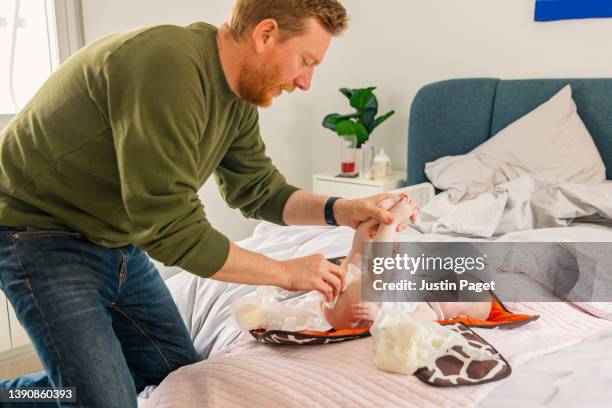 mature father changing his baby daughter's nappy in the bedroom - nappy change imagens e fotografias de stock