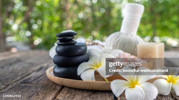 spa herbal compressing ball with candles and frangipani flowers - thai massage stock-fotos und bilder