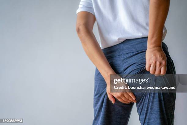 midsection of a woman with hands-on buttocks standing against. - woman hemorrhoids fotografías e imágenes de stock