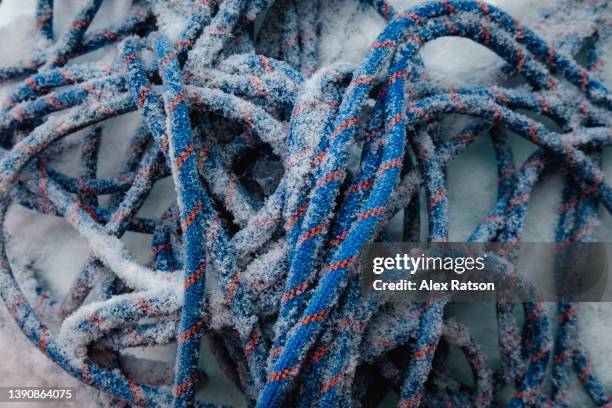 detail shot of an ice covered rope lays in the snow - kletterseil stock-fotos und bilder