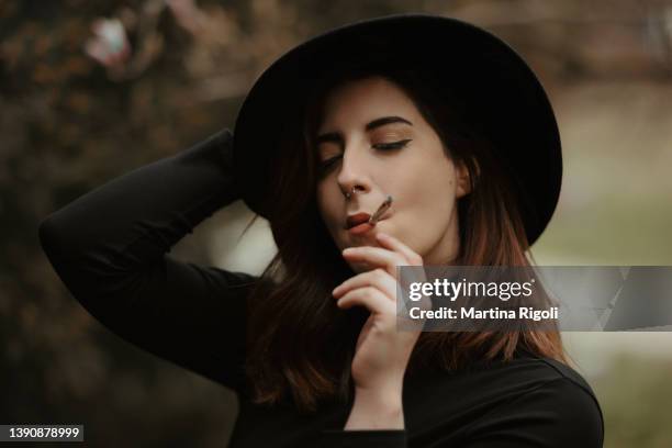 junges rothaariges frauenporträt, alle in schwarz gekleidet rauchende zigarette mit geschlossenen augen - pale complexion stock-fotos und bilder