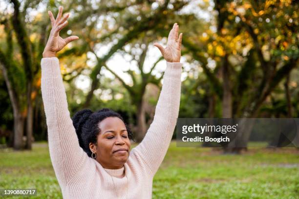 black african american woman doing yoga outdoors with eyes closed - woman happy raised arms closed eyes stock pictures, royalty-free photos & images