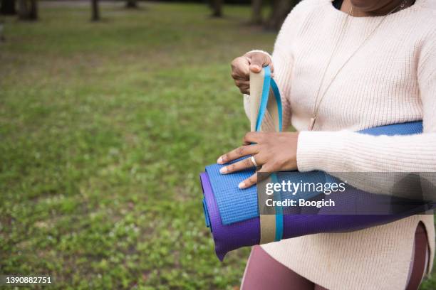 hands of african american woman tightening the strap on her yoga mat - strap stock pictures, royalty-free photos & images