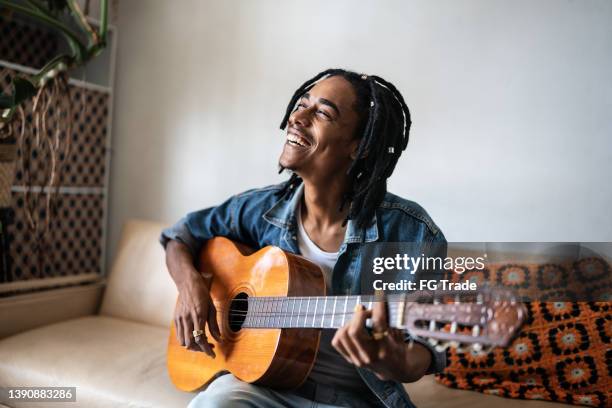 young man playing guitar at home - musical instrument stock pictures, royalty-free photos & images