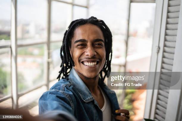 young man on a taking selfie at home - camera point of view - zelfportret stockfoto's en -beelden