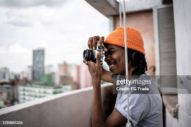 young man taking photos from apartment's porch - man photographer stock pictures, royalty-free photos & images