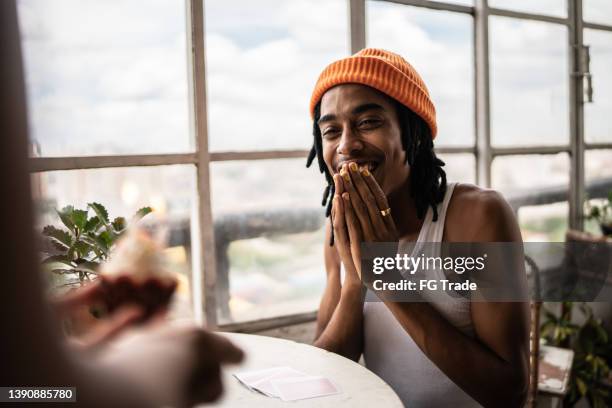 joven recibiendo un cupcake de cumpleaños en casa - mano tapando la boca fotografías e imágenes de stock