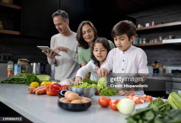 familienkochen zu hause nach einem rezept auf einem tablet - children cooking school stock-fotos und bilder