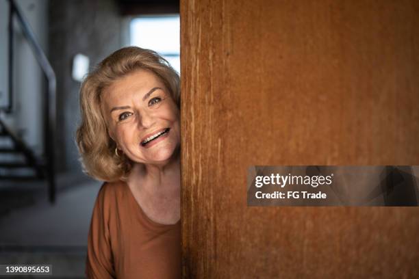 portrait of a senior woman opening the door - woman greeting stock pictures, royalty-free photos & images