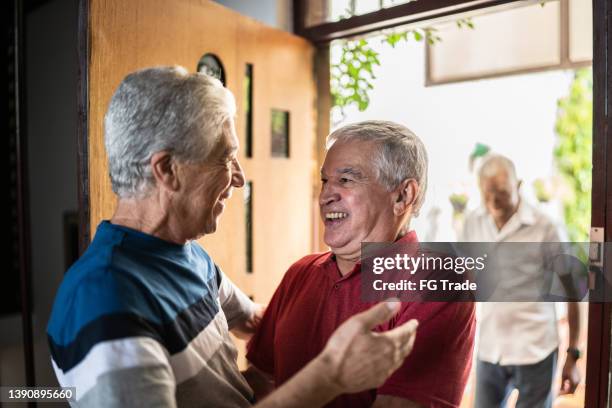 senior man welcoming a friend at home - old brother stock pictures, royalty-free photos & images