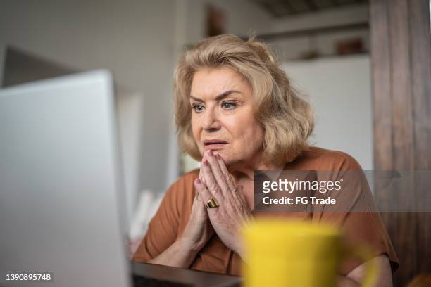 shock senior woman using the laptop at home - mysterious blond woman stock pictures, royalty-free photos & images
