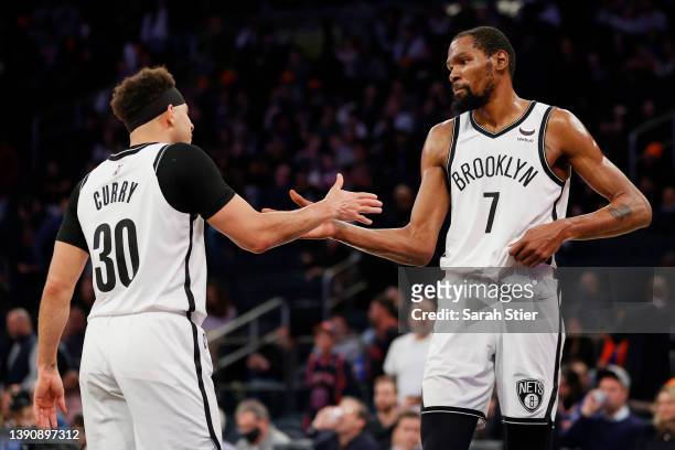 Kevin Durant high-fives Seth Curry of the Brooklyn Nets during the second half against the New York Knicks at Madison Square Garden on April 06, 2022...
