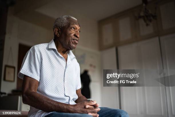 senior man sitting on the bed and looking away - prayer solitude stock pictures, royalty-free photos & images