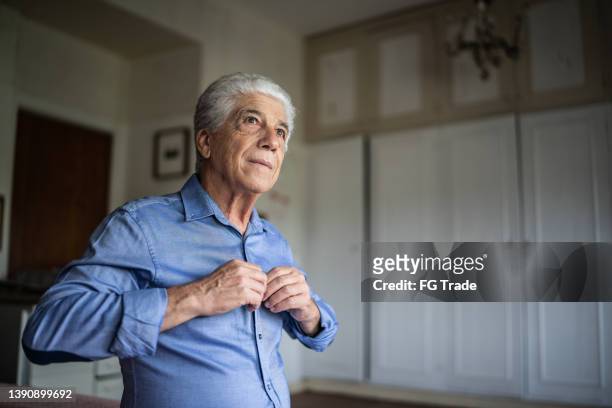 hombre mayor vistiendo una camisa en casa - un solo hombre mayor fotografías e imágenes de stock