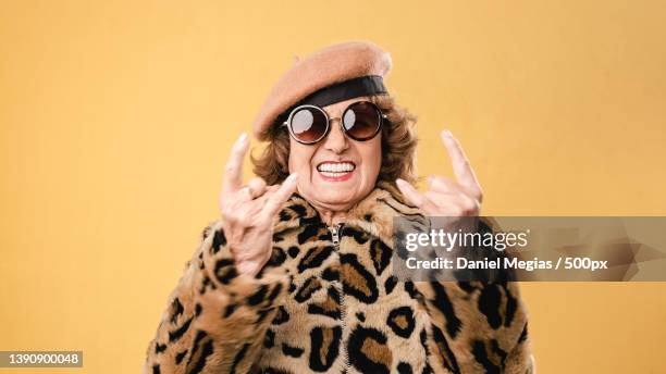 stylish senior woman showing rock n roll gesture - coole oma stock-fotos und bilder