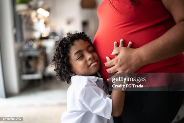 hijo pequeño poniendo la mano en el estómago de las madres embarazadas en casa - baby touching belly fotografías e imágenes de stock