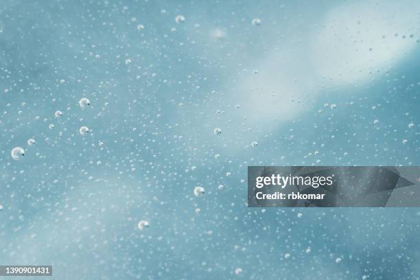 lots of bubbles in clear fresh water on blue background - carbonation foto e immagini stock