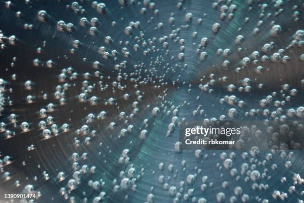 abstract dark background - close-up bubbles of boiling water on a metal circle surface - sparkling water glass stockfoto's en -beelden