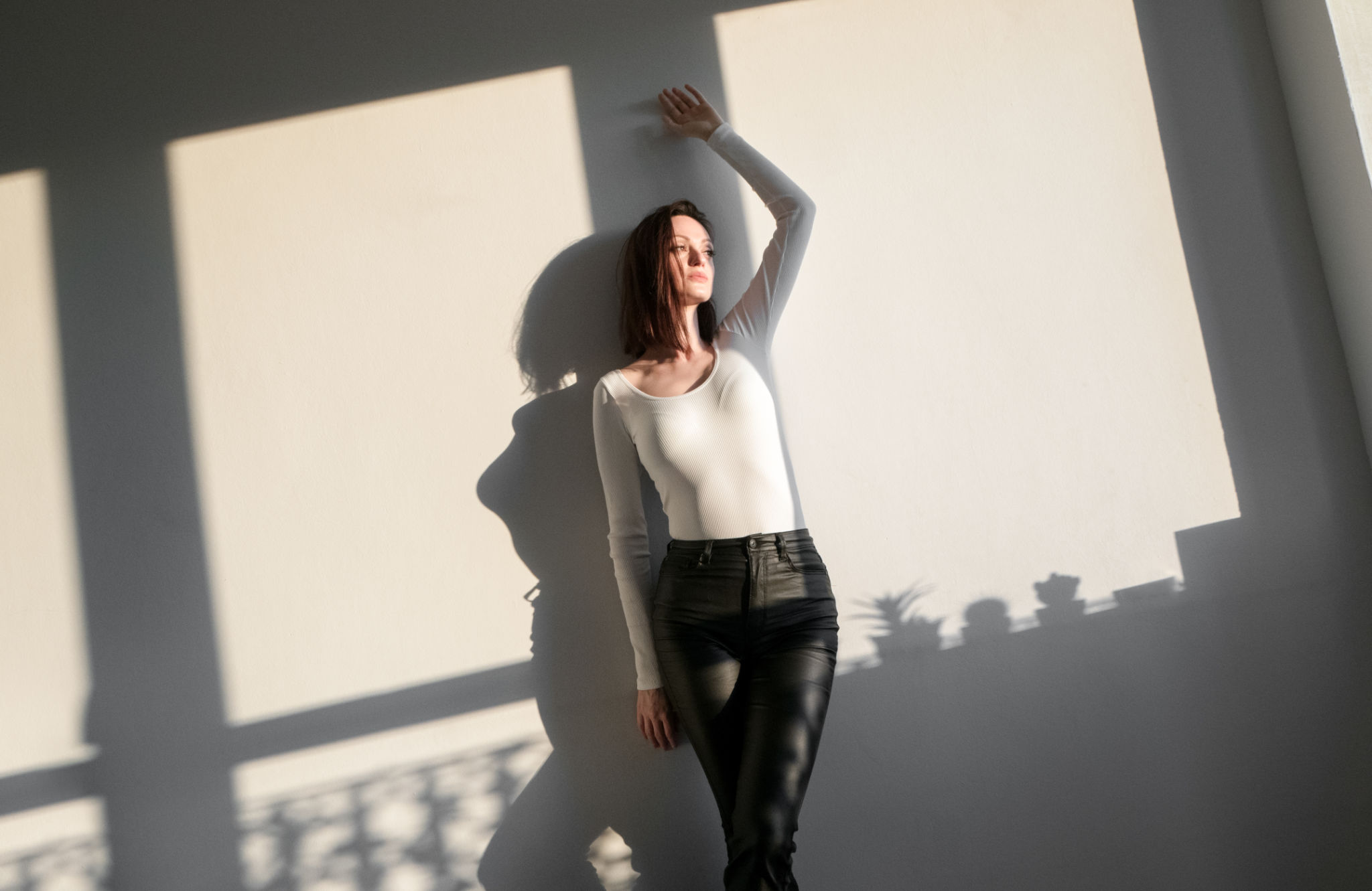Confident brunette leaning against the wall indoor Confident brunette leaning against the wall indoor