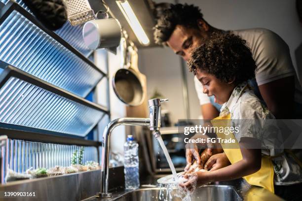 father and son washing dishes at home - child washing hands stockfoto's en -beelden