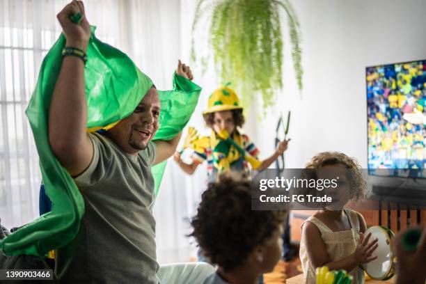 father with children cheering for brazilian soccer team at home - brazil girls supporters stock pictures, royalty-free photos & images