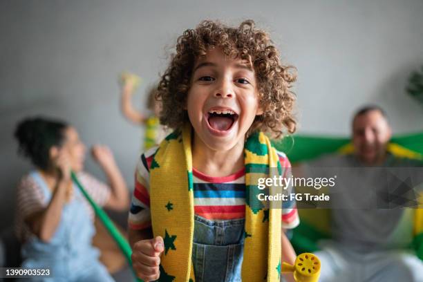 portrait d’un garçon encourageant l’équipe de football brésilienne avec sa famille à la maison - enfant crier photos et images de collection