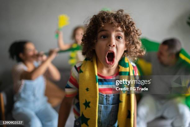boy cheering for brazilian team with family at home - a brazil supporter stockfoto's en -beelden