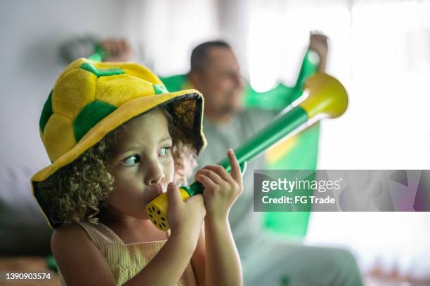 girl with a vuvuzela with her family cheering brazilian soccer team at home - brazil girls supporters stock pictures, royalty-free photos & images
