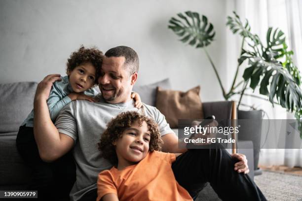 father and sons watching tv at home - spectator parent stock pictures, royalty-free photos & images