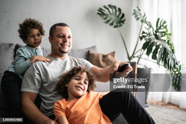 father and sons watching tv at home - changing-channels stock pictures, royalty-free photos & images