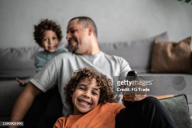 portrait of a boy watching tv with his father and brother at home - tv audience stock pictures, royalty-free photos & images