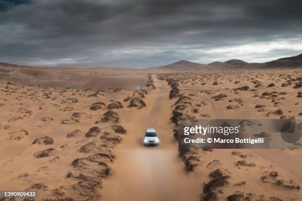 car driving on dirt track in the desert, fuerteventura, spain. - desert road stock pictures, royalty-free photos & images