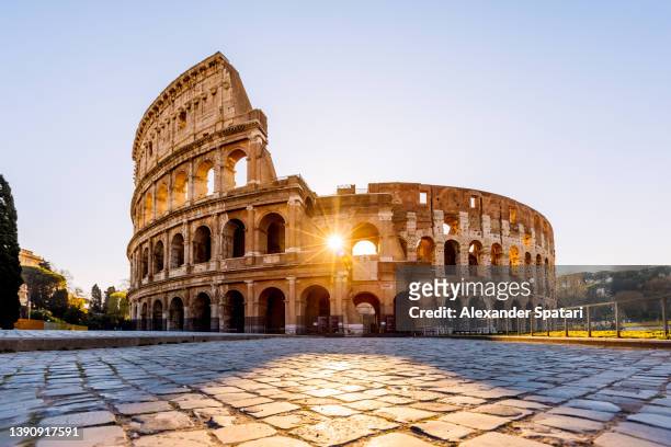 sun shining through the arches of coliseum at sunrise, rome, italy - rom stock-fotos und bilder