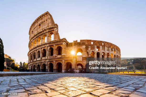 sun shining through the arches of coliseum at sunrise, rome, italy - romeinse rijk stockfoto's en -beelden