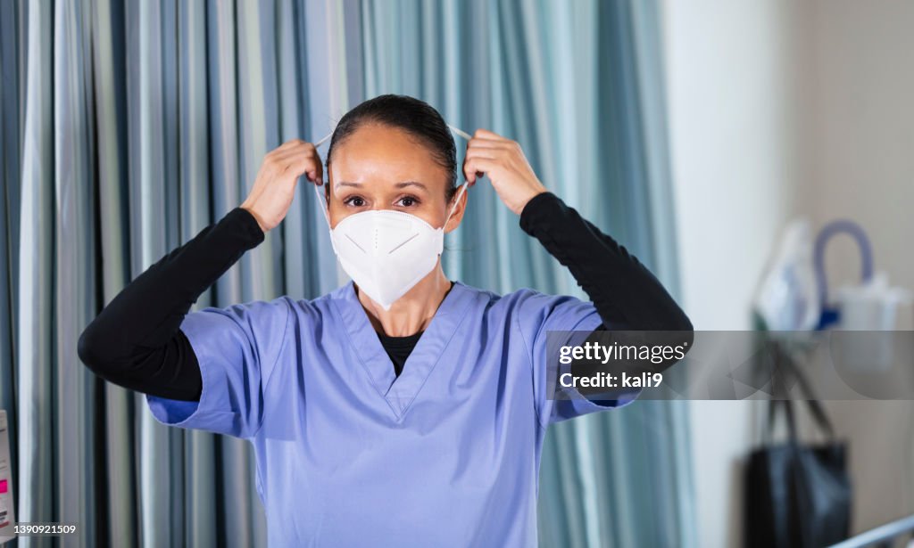 Female nurse putting on N95 face mask