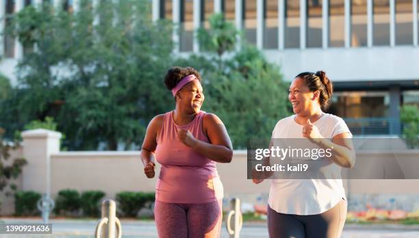 two multiracial women exercising in city, jogging - plus size stock pictures, royalty-free photos & images